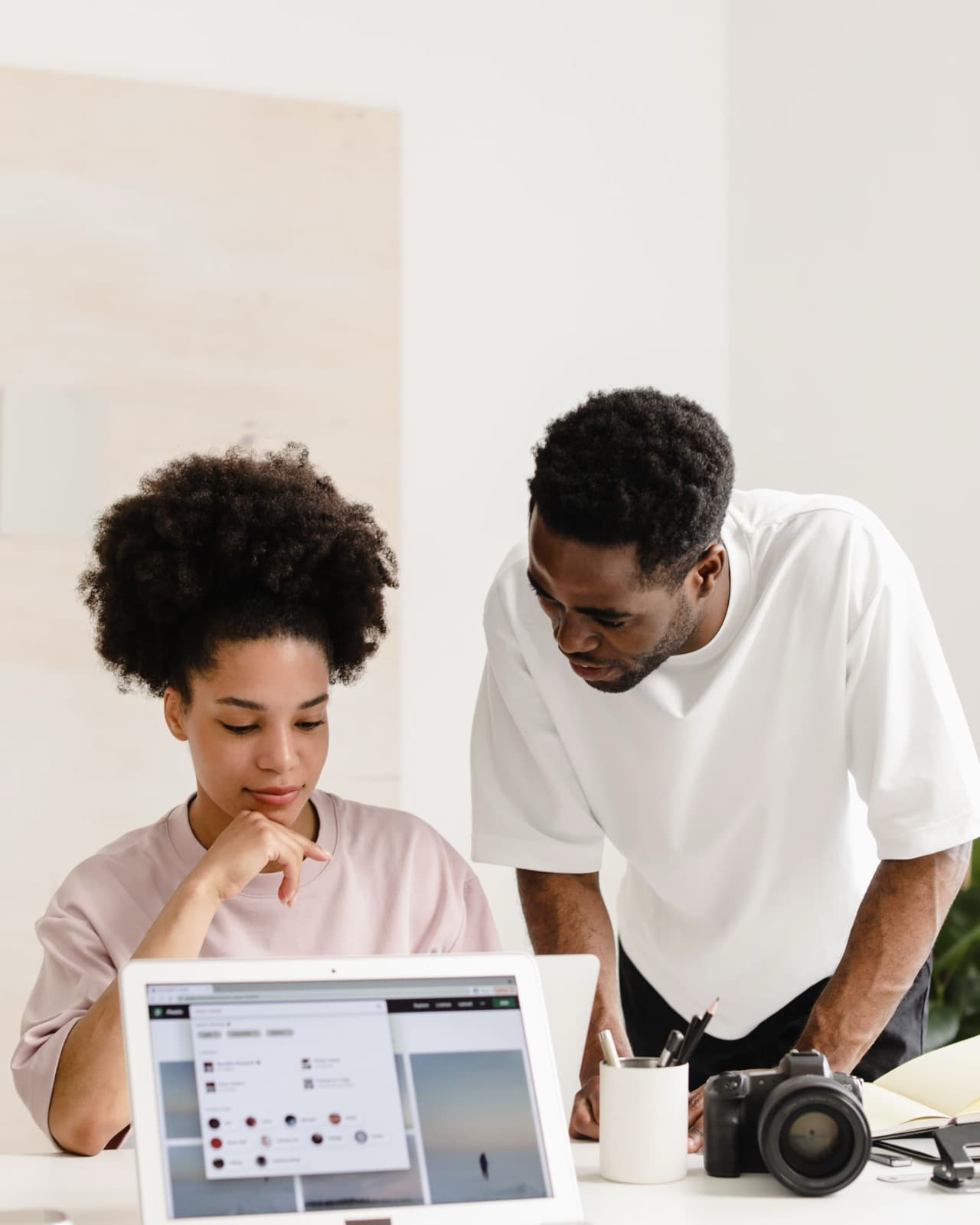 Two colleagues reviewing a laptop together at a shared desk.