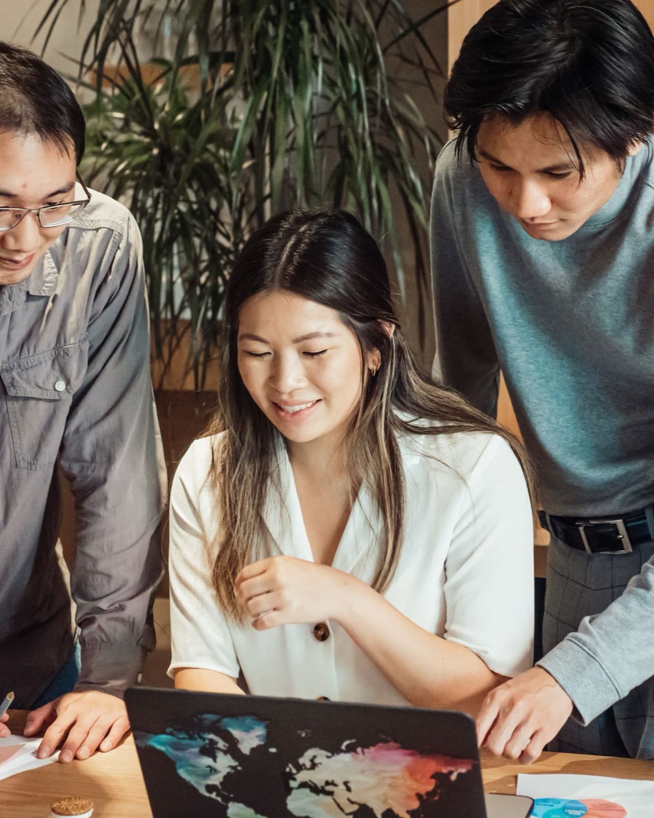 Three colleagues gathering around a laptop and notes during a project review.