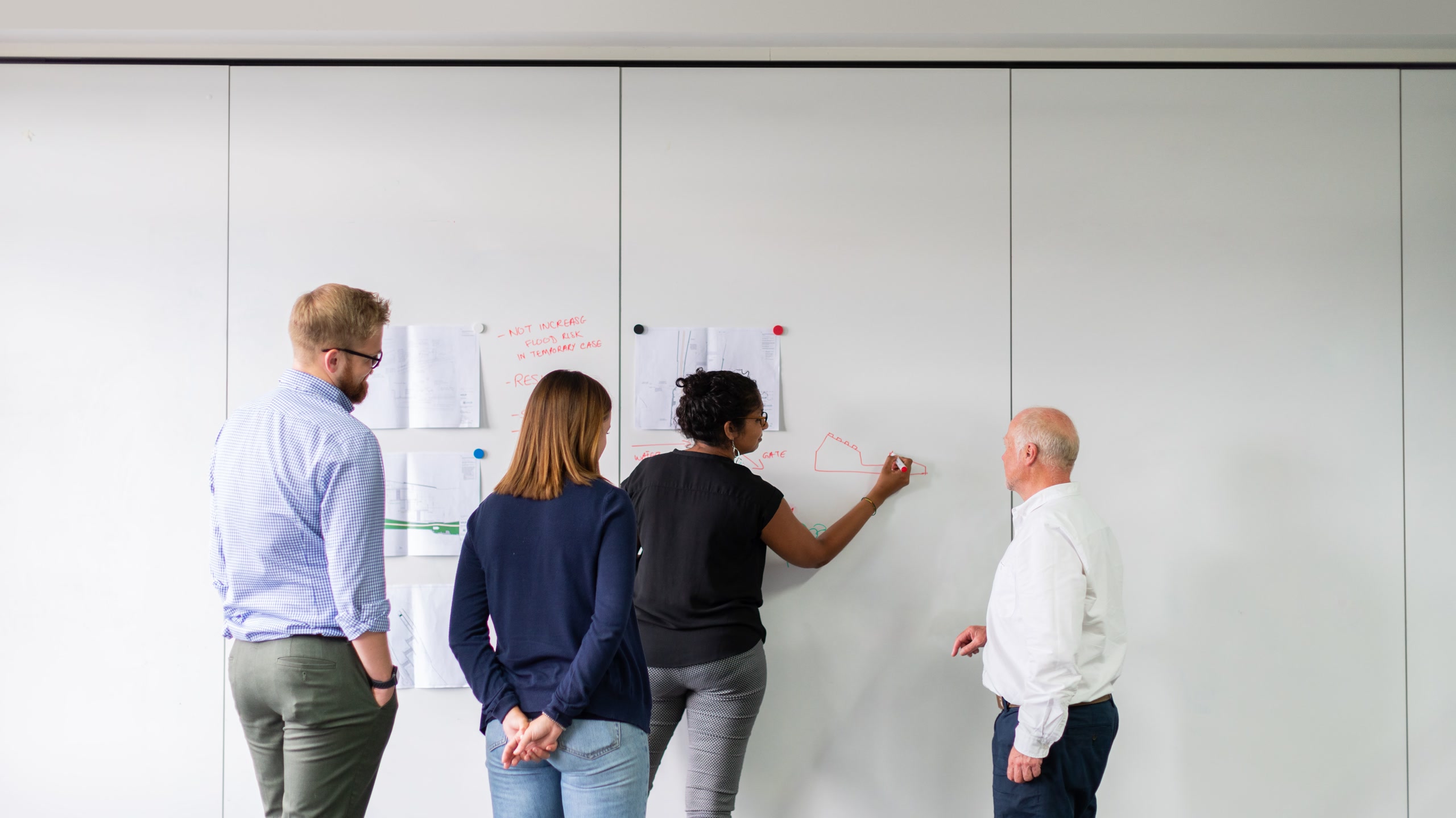Four colleagues planning together in front of a large whiteboard.